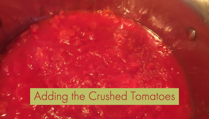 adding crushed tomatoes to chili