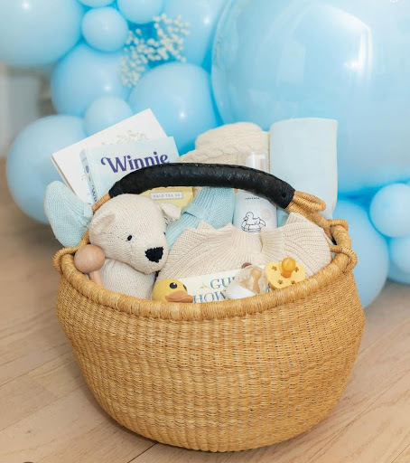A blue-themed baby gift basket with a toy, soft towel, teether, wooden toy, and more from Our Green House.