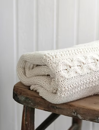 Stack of cream handknit blankets with “handmade with love” text from Our Green House.
