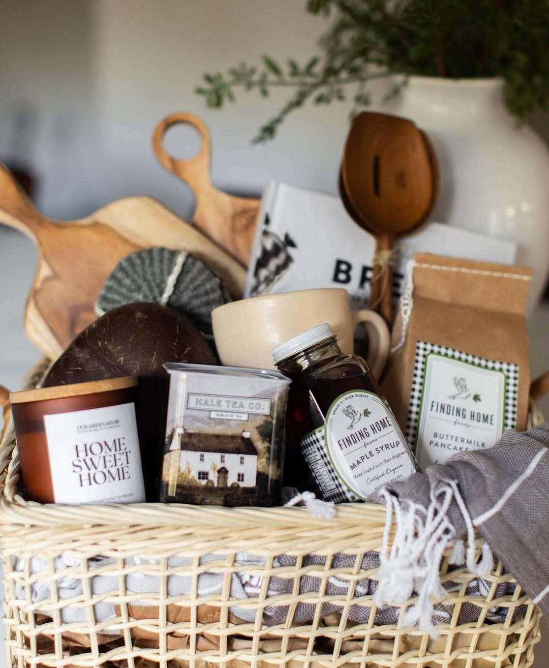 Cozy gift basket from Our Green House with tea, syrup, a candle, and kitchen essentials.