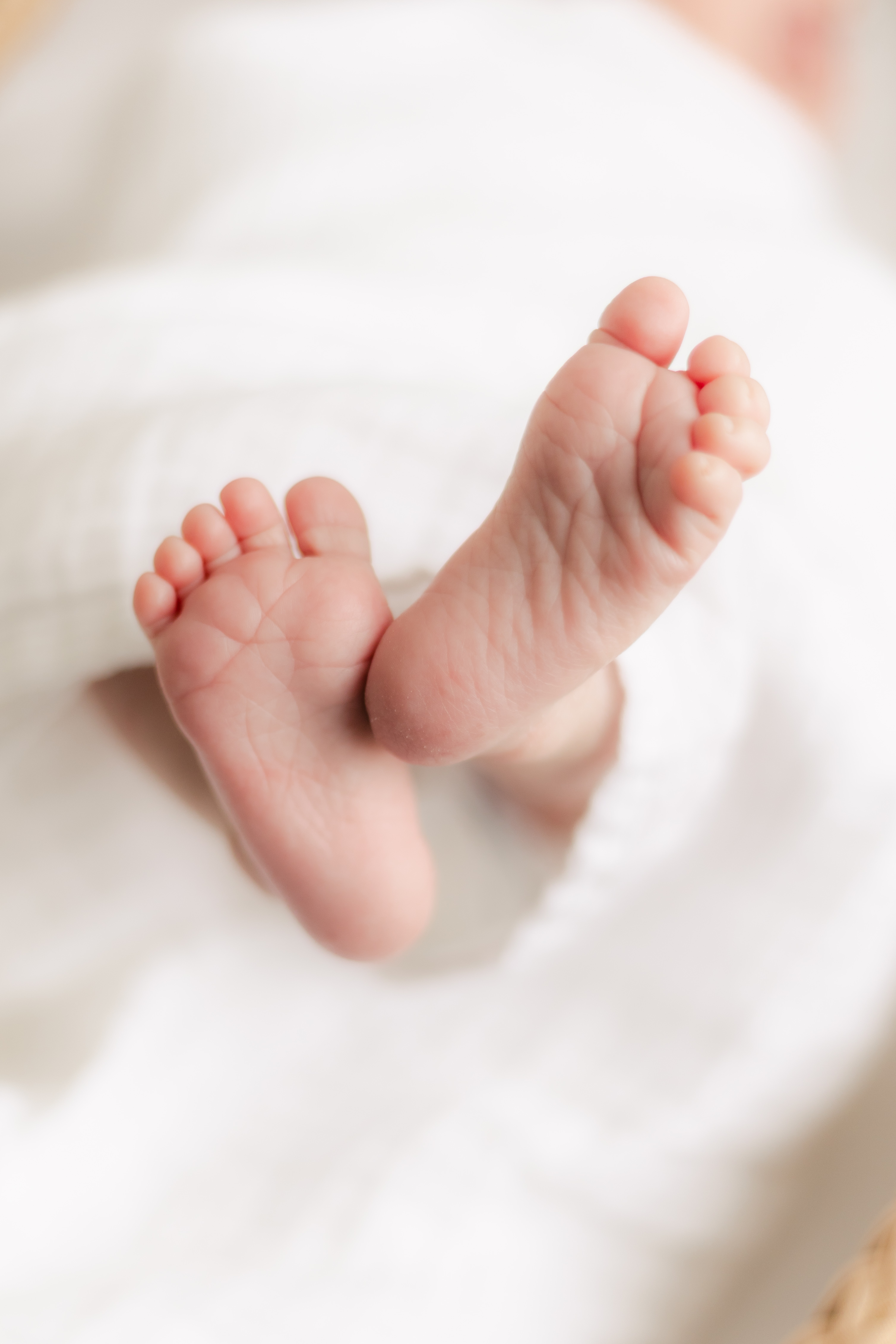 close-up of a newborn baby&rsquo;s feet wrapped in a soft white blanket from Our Green House.