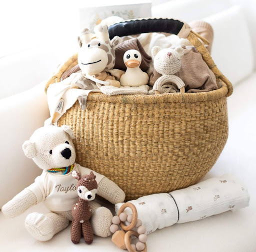 Woven baby gift basket with plush toys and neutral essentials from Our Green House.