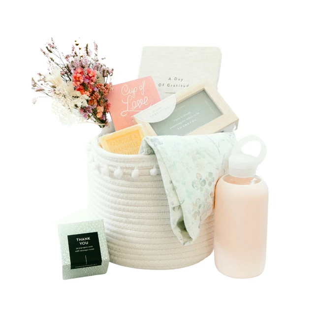 Our Green House thank-you gift basket with dried flowers, candle, keepsake box, pink water bottle, and soft cloth in a white rope basket.
