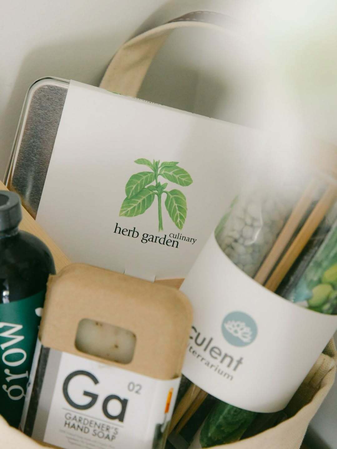 Close-up of Our Green House gift basket with herb garden kit, hand soap, terrarium, and eco-friendly essentials.