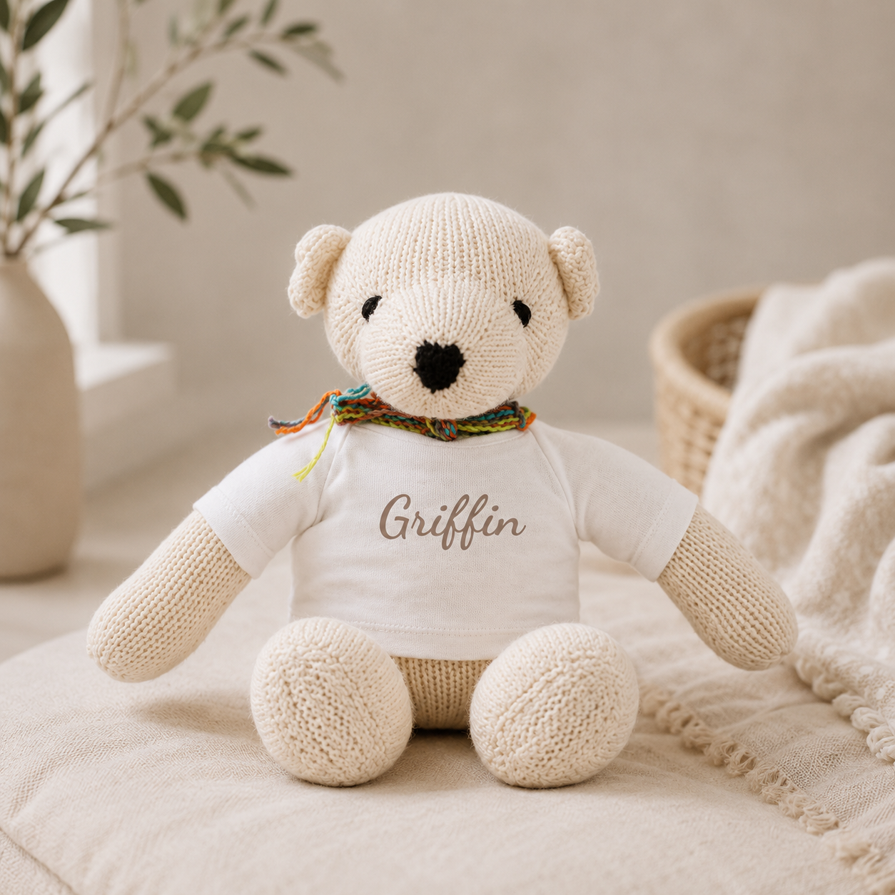 Knit teddy bear wearing a personalized shirt with the name Griffin and a colorful striped scarf, displayed as a keepsake baby gift.