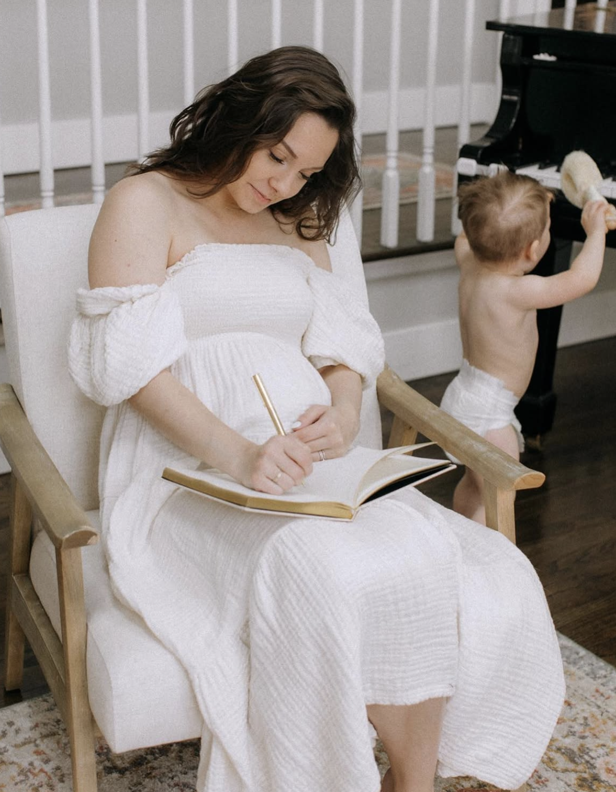 Expecting mother journaling beside her baby while enjoying a calm self-care moment with Our Green House products.