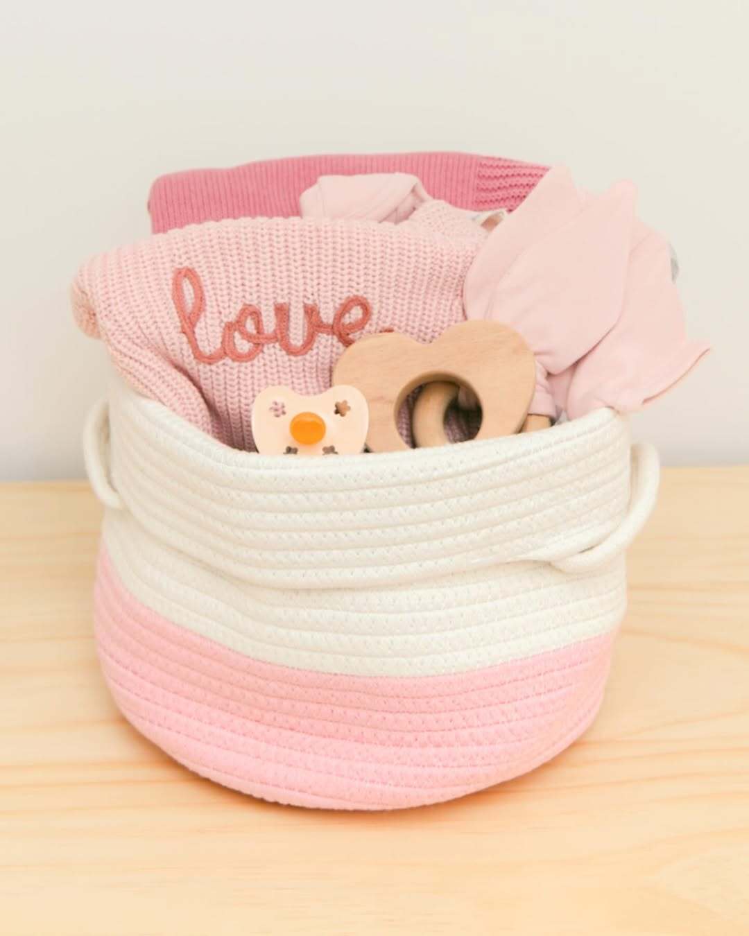 Pink and white Our Green House basket with baby blanket, wooden toys, and essentials.