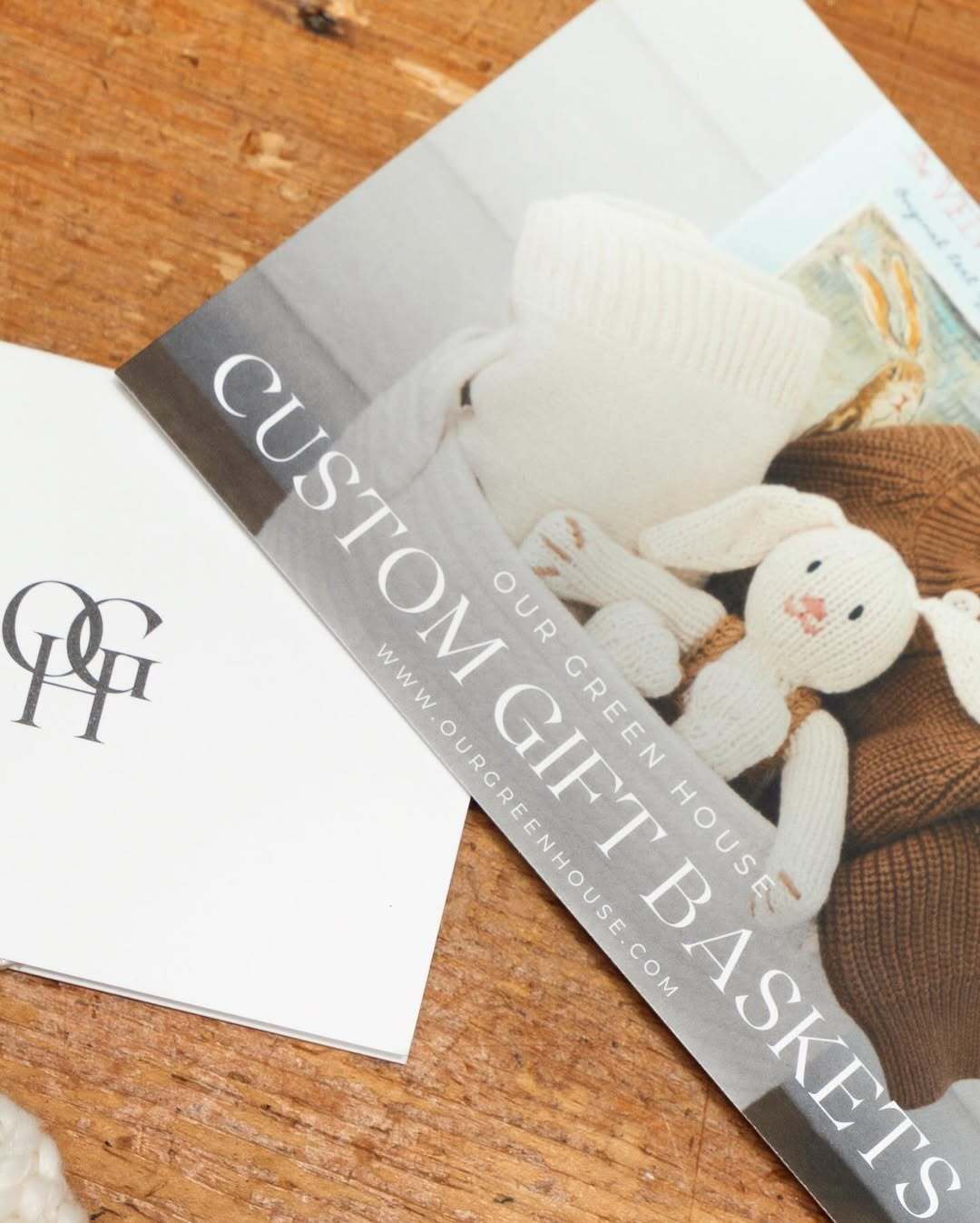 Printed ‘Custom Gift Baskets’ brochure from Our Green House on a wooden surface, showcasing personalization options.