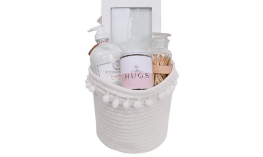 Our Green House sympathy gift basket arranged in a reusable container with a soft blanket, candle, and comfort-focused goodies, styled as a warm &ldquo;sending hugs&rdquo; gift.