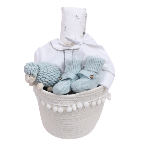 A white rope basket with baby gifts: a knitted sheep, booties, and white clothes from Our Green House.