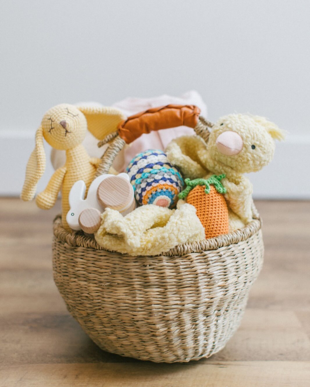 A woven basket from Our Green House filled with plush and crochet toys, ideal for a thoughtful baby gift.